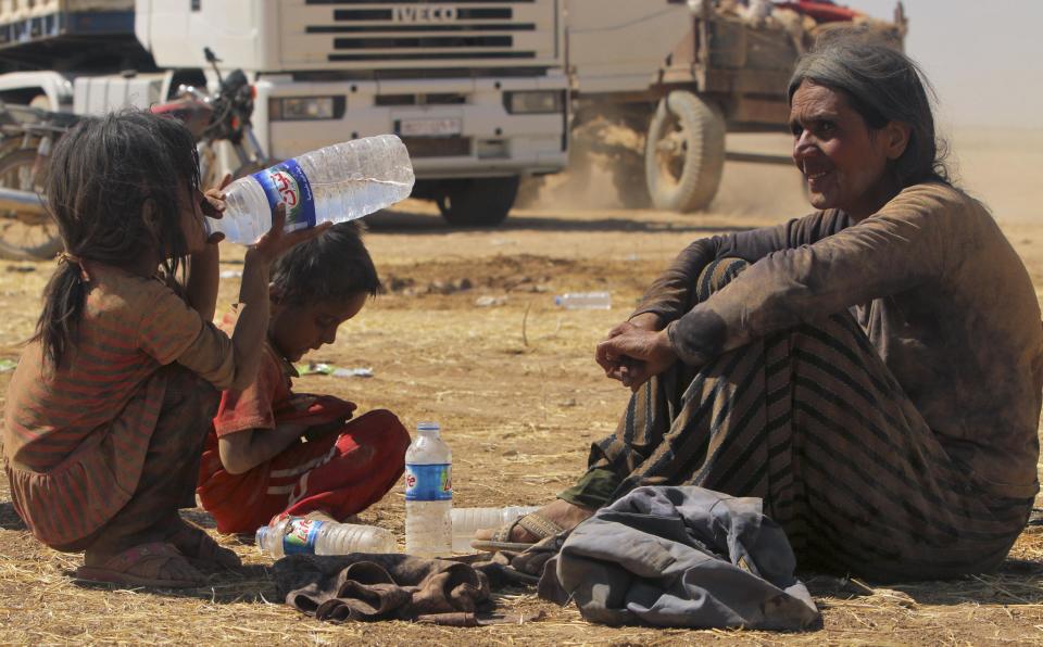 Displaced people from the minority Yazidi sect, fleeing violence from forces loyal to the Islamic State in Sinjar town, rest as they make their way towards the Syrian border, on the outskirts of Sinjar mountain, near the Syrian border town of Elierbeh of A