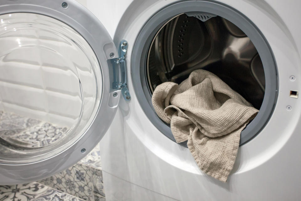 A grey towel sits inside a washing machine ready to be laundered