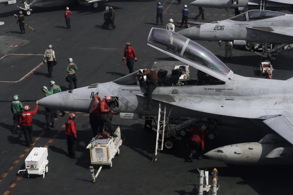 Crew members work on an F/A-18 Super Hornet fighter jet on the deck of the U.S. Navy USS Ronald Reagan in the South China Sea, Tuesday, Nov. 20, 2018.