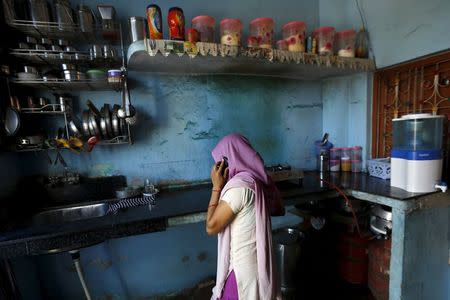 The mother of Meenakshi Kumari, 23, one of the two sisters allegedly threatened with rape by a village council in the northern Indian state of Uttar Pradesh, speaks on a mobile phone inside the kitchen of her house at Sankrod village in Baghpat district, India, September 1, 2015. REUTERS/Adnan Abidi