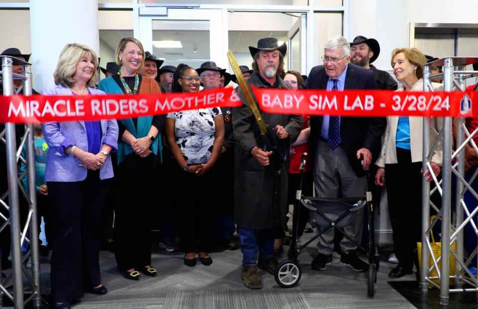 Scott Ressmeyer, co-owner of Country’s Barbecue and founder of the Miracle Ride, center, cuts the ribbon Thursday afternoon during a celebration of the new mother-baby simulation lab at Columbus State University’s School of Nursing. The lab has been named in honor of Dr. Cecil F. Whitaker, M.D., to Ressmeyer’s immediate left. Whitaker is a retired OB-GYN. 03/28/2024