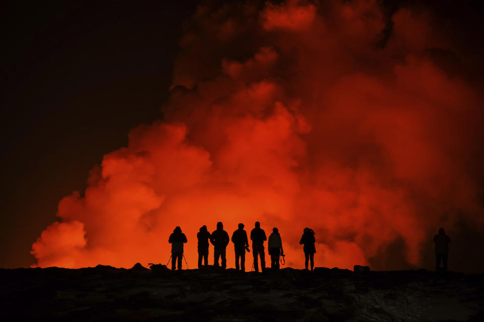 People look at the volcano erupting, north of Grindavík, Iceland, Thursday, Feb. 8, 2024. Iceland’s Meteorological Office says a volcano is erupting in the southwestern part of the country, north of a nearby settlement. The eruption of the Sylingarfell volcano began at 6 a.m. local time on Thursday, soon after an intense burst of seismic activity. (AP Photo/Marco Di Marco)