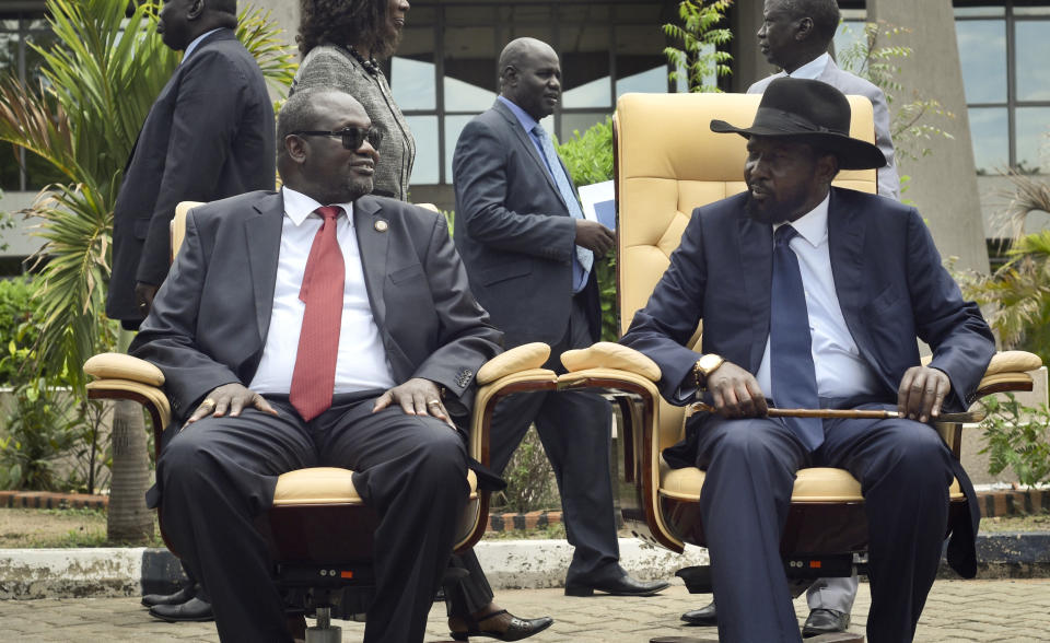 FILE - In this Friday, April 29, 2016 file photo, then South Sudan's First Vice President Riek Machar, left, looks across at President Salva Kiir, right, as they sit to be photographed following the first meeting of a new transitional coalition government, in the capital Juba, South Sudan. It seems Friday Oct. 26, 2018, that South Sudan's government is spending millions of dollars next week to celebrate a "final final" peace deal to end a five-year civil war. The problem is, the rebel leader who agreed to share power is reluctant to come home. Riek Machar's hesitation and condition-setting amid security concerns is the latest sign that one of Africa's deadliest conflicts might be merely on pause. (AP Photo/Jason Patinkin, File)