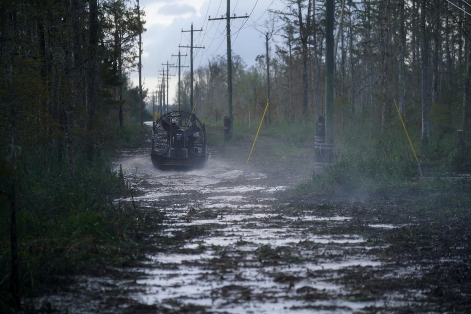 Electrical workers ride through marsh in an airboat to restore power lines in the aftermath of Hurricane Ida in Houma, La., Friday, Sept. 17, 2021. The Louisiana terrain presents special challenges. In some areas, lines thread through thick swamps that can be accessed only by air boat or marsh buggy, which looks like a cross between a tank and a pontoon boat. Workers don waders to climb into muddy, chest-high waters home to alligators and water moccasins. (AP Photo/Gerald Herbert)