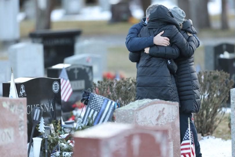 Cindy Chesna stands at the Blue Hills Cemetery grave in Braintree of her late husband, Weymouth police Sgt. Michael Chesna, after a jury found the shooter guilty of murder at his second trial on Friday, Feb. 16, 2024. With Chesna is her sister, Debbie Comperchio, and Debbie's husband.