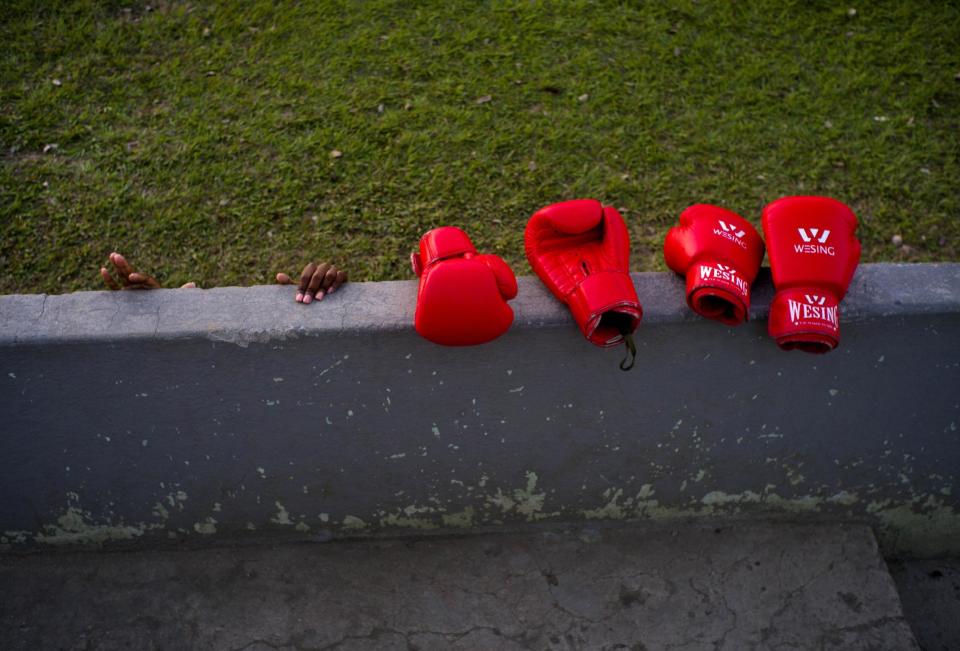 In this Jan. 19, 2017 photo, boxer Legnis Cala's hands grab a wall, next to boxing gloves during a warm-up prior to a training session, in Havana, Cuba. Officials have said they're analyzing whether to allow women to box and say they are carrying out medical studies to understand the impact of blows to a woman's body and whether such action is "appropriate." (AP Photo/Ramon Espinosa)