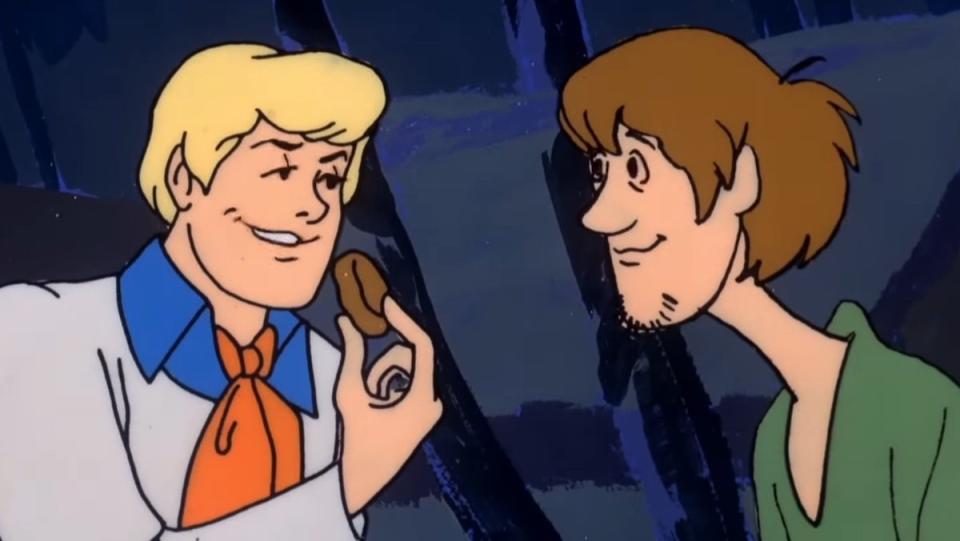 Fred holds up a Scooby Snack to Shaggy on Scooby Doo