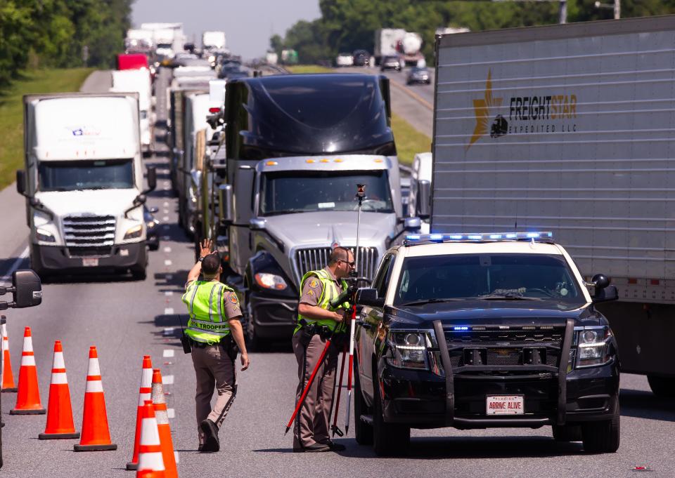 Florida Highway Patrol Trooper Cpl. Justin Bard, right, prepares to take pictures and map out the scene of a fatal crash on Wednesday morning near the Irvine/McIntosh exit on Interstate 75.