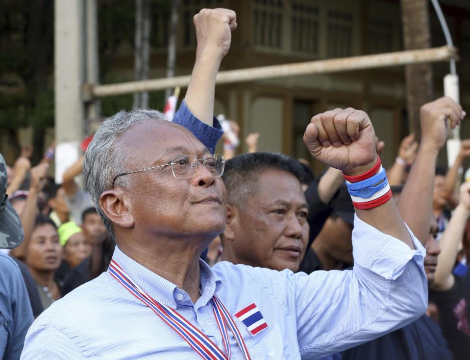 Anti-government protest leader Suthep Thaugsuban, left, raises his clenched fist with supporters after singing national anthem during a rally outside the parliament in Bangkok, Thailand Monday, May 12, 2014. Emboldened by the removal of Thailand's prime minister, anti-government protesters withdrew from the city's main park Monday and marched to the vacated prime minister's office compound - where the protest leader has pledged to set up his new office. (AP Photo/Apichart Weerawong)