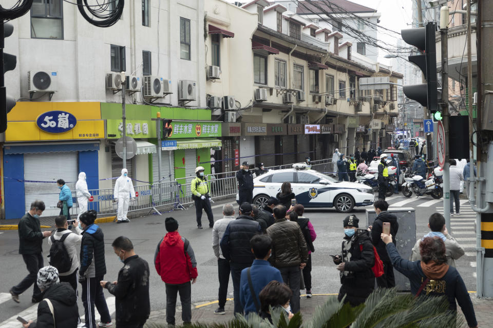 Bystanders watch as police officers and workers in protective suits close off a neighborhood as it is placed under lockdown in Shanghai, China, Thursday, Jan. 21, 2021. Shanghai has imposed lockdowns on two of China's best-known hospitals and some surrounding residential communities after they were linked to new coronavirus cases. (Chinatopix via AP)