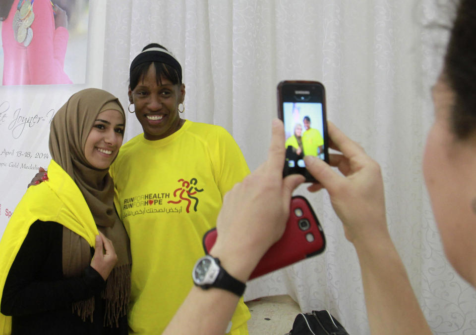 American track and field great Jackie Joyner-Kersee poses with a Palestinian woman in the West Bank city of Ramallah, Thursday , April 17, 2014. The three-time Olympic gold medalist visited the West Bank to encourage Palestinian women to be physically active. (AP Photo/Nasser Shiyoukhi)