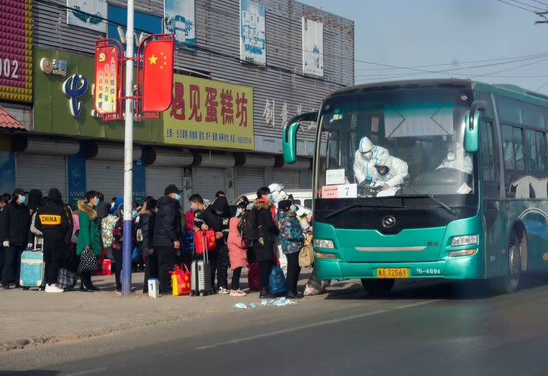 People who are required to undergo centralized quarantine line up to board a bus in Shijiazhuang