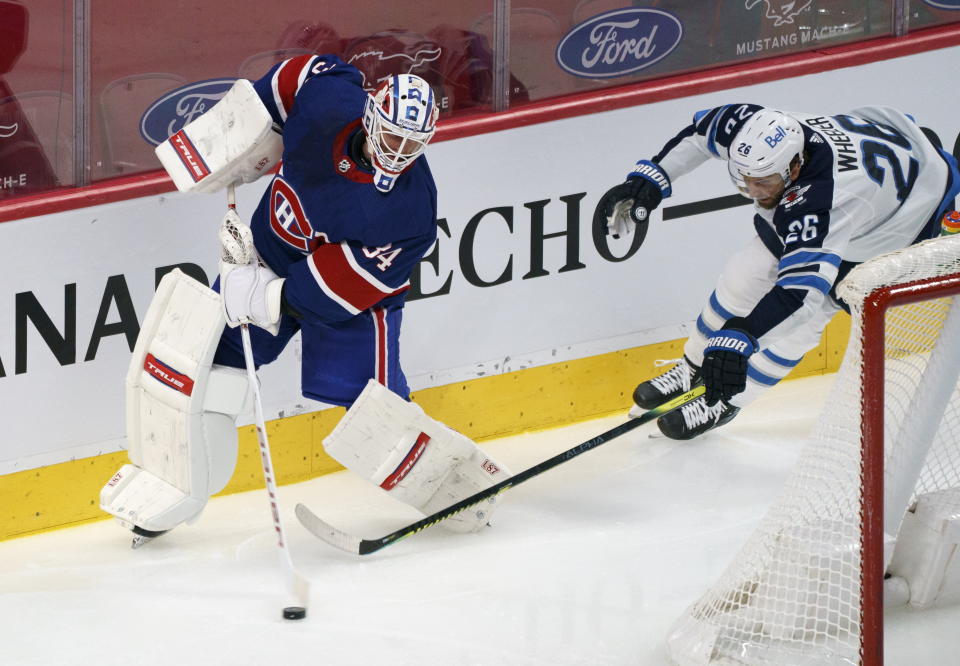 Montreal Canadiens goaltender Jake Allen clears the puck away from Winnipeg Jets' Blake Wheeler during second-period NHL hockey game action in Montreal, Thursday, March 4, 2021. (Paul Chiasson/The Canadian Press via AP)