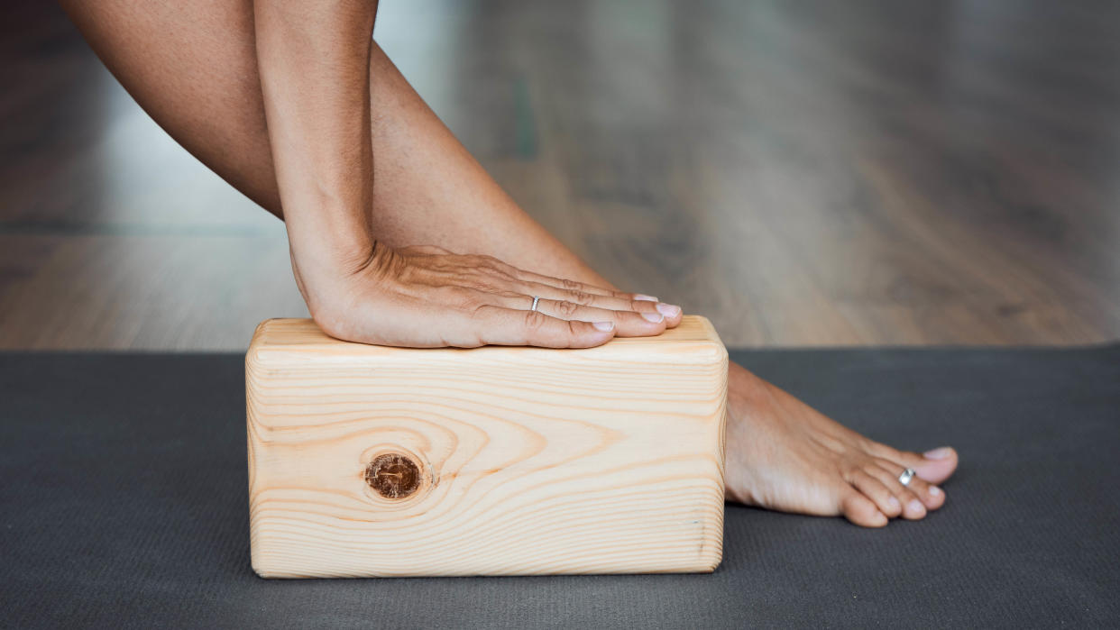  A wooden yoga block being used during a stretch. 