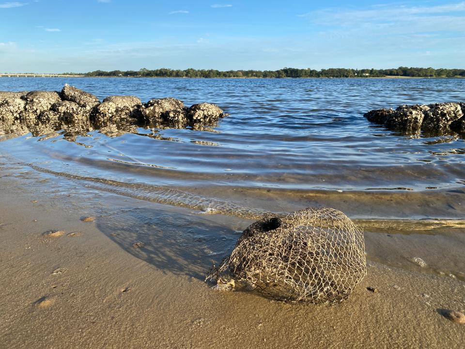 An empty oyster bag from the Navy Point Living Shoreline project lies on the sand at Gibbs Point in Navy Point Park at low-tide on Tuesday.