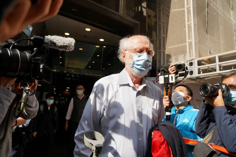 American lawyer John Clancey walks out of a building as he is taken away by police officers in Hong Kong