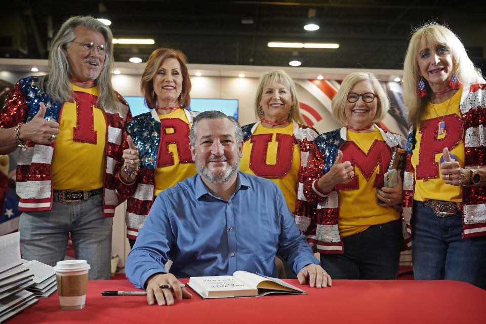 Cinco partidarios del expresidente Donald Trump posan detrás del senador Ted Cruz, republicano por Texas, durante la firma de un libro en la Conferencia de Acción Política Conservadora (CPAC) en Dallas, el 5 de agosto de 2022. (AP Foto/LM Otero)