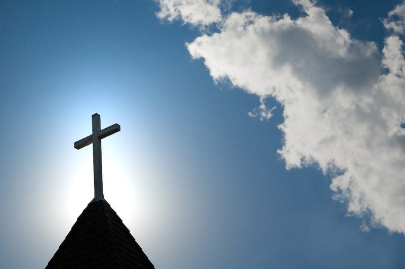 A wood cross on an old church steeple backlighted by a rising sun. - Photo: wwing (Getty Images)