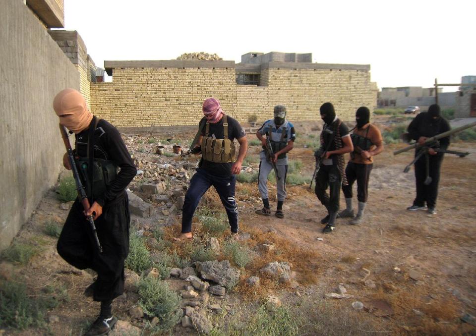 In this Monday, April 28, 2014 photo, masked anti-government gunmen move with their weapons as they patrol in Fallujah, Iraq. Al-Qaida-linked fighters and their allies seized the city of Fallujah and parts of the Anbar provincial capital Ramadi in late December after authorities dismantled a protest camp. Like the camp in the northern Iraqi town of Hawija whose dismantlement in April sparked violent clashes and set off the current upsurge in killing, the Anbar camp was set up by Sunnis angry at what they consider second-class treatment by the Shiite-led government. (AP Photo)