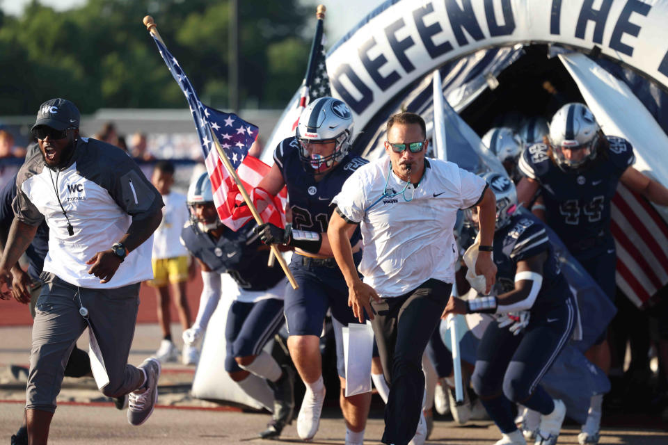 West Clermont head coach Nate Mahon leads the Wolves on to the field against Hamilton Friday, Aug. 19, 2022.