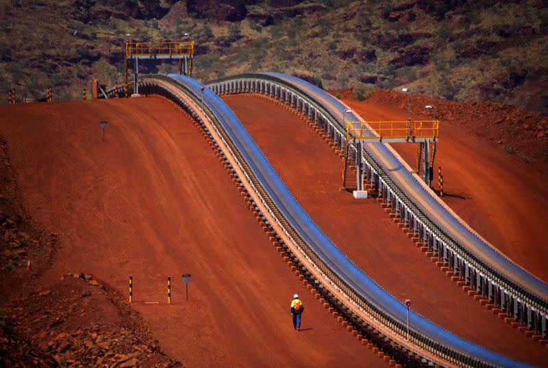 FILE PHOTO: Worker walks near conveyer belts loaded with iron ore at the Fortescue Solomon iron ore mine located in the Valley of the Kings
