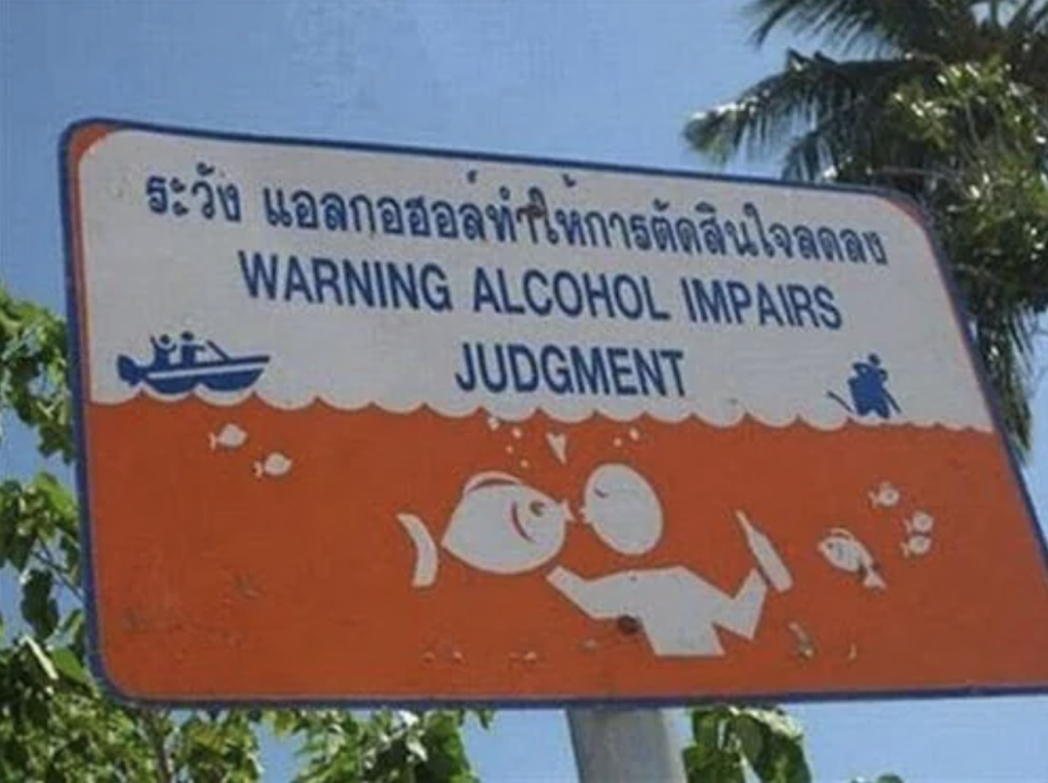 Sign with a message "WARNING ALCOHOL IMPAIRS JUDGMENT" featuring a pictogram of a person drinking and fish underwater