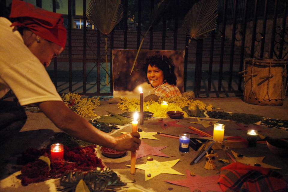 Una mujer coloca una vela frente a una foto de la asesinada activista ambiental Berta Cáceres, durante una ceremonia en su honor ante la Corte Suprema en Tegucigalpa, Honduras, el domingo 16 de septiembre de 2018. El juicio a ocho hombres acusados del asesinato de Cáceres fue pospuesto esta semana. (AP Foto/Fernando Antonio)