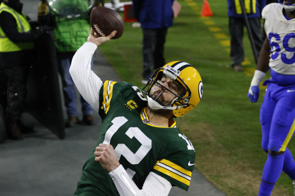 Green Bay Packers quarterback Aaron Rodgers throws the ball to fans after scoring on a one-yard touchdown run against the Los Angeles Rams during the first half of an NFL divisional playoff football game, Saturday, Jan. 16, 2021, in Green Bay, Wis. (AP Photo/Matt Ludtke)