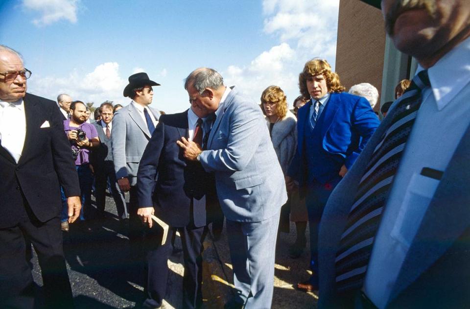 February 15, 1984: Fritz Von Erich, center, is seen speaking to another man in a crowd of people gathered to attend the funeral of his son, David Von Erich, held at the First Baptist Church in Denton, TX. Kerry Von Erich is seen in the blue suit to the right.