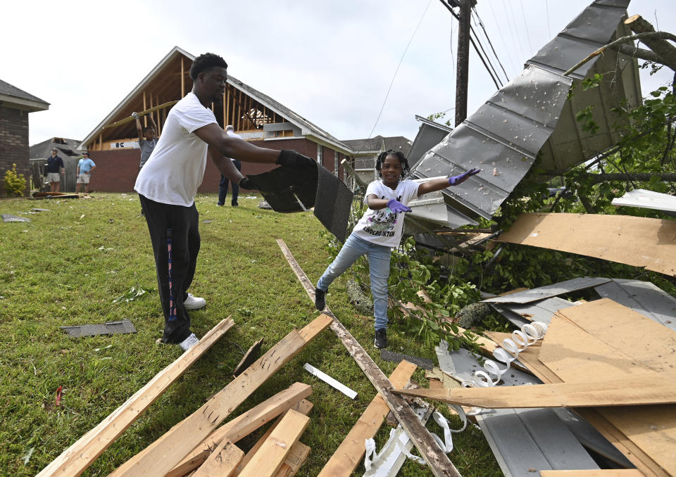 Derrick Pounds and his daughter, Madison, 6, clean up debris around their residence on Elvis Presley Drive in Tupelo, Miss., Monday, May 3, 2021. Multiple tornadoes were reported across the state on Sunday. (AP Photo/Thomas Graning)