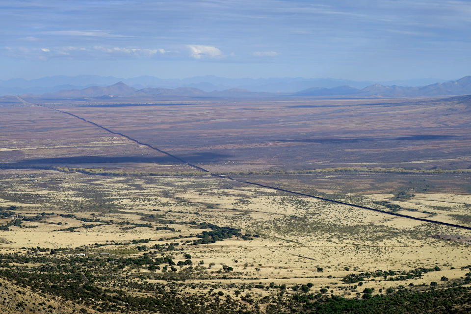 With Mexico to the right, the border wall cuts through the Sonoran Desert, Wednesday, Dec. 9, 2020, as seen from atop Montezuma's Pass in Coronado National Memorial, in Hereford, Ariz. Construction of the border wall, mostly in government owned wildlife refuges and Indigenous territory, has led to environmental damage and the scarring of unique desert and mountain landscapes that conservationists fear could be irreversible. (AP Photo/Matt York)