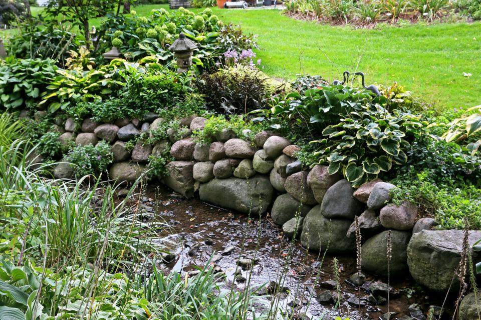 Perennials and annuals accent the area where Judy  Schmidt added boulders to enhance a ditch and reduce erosion at her Franklin home.