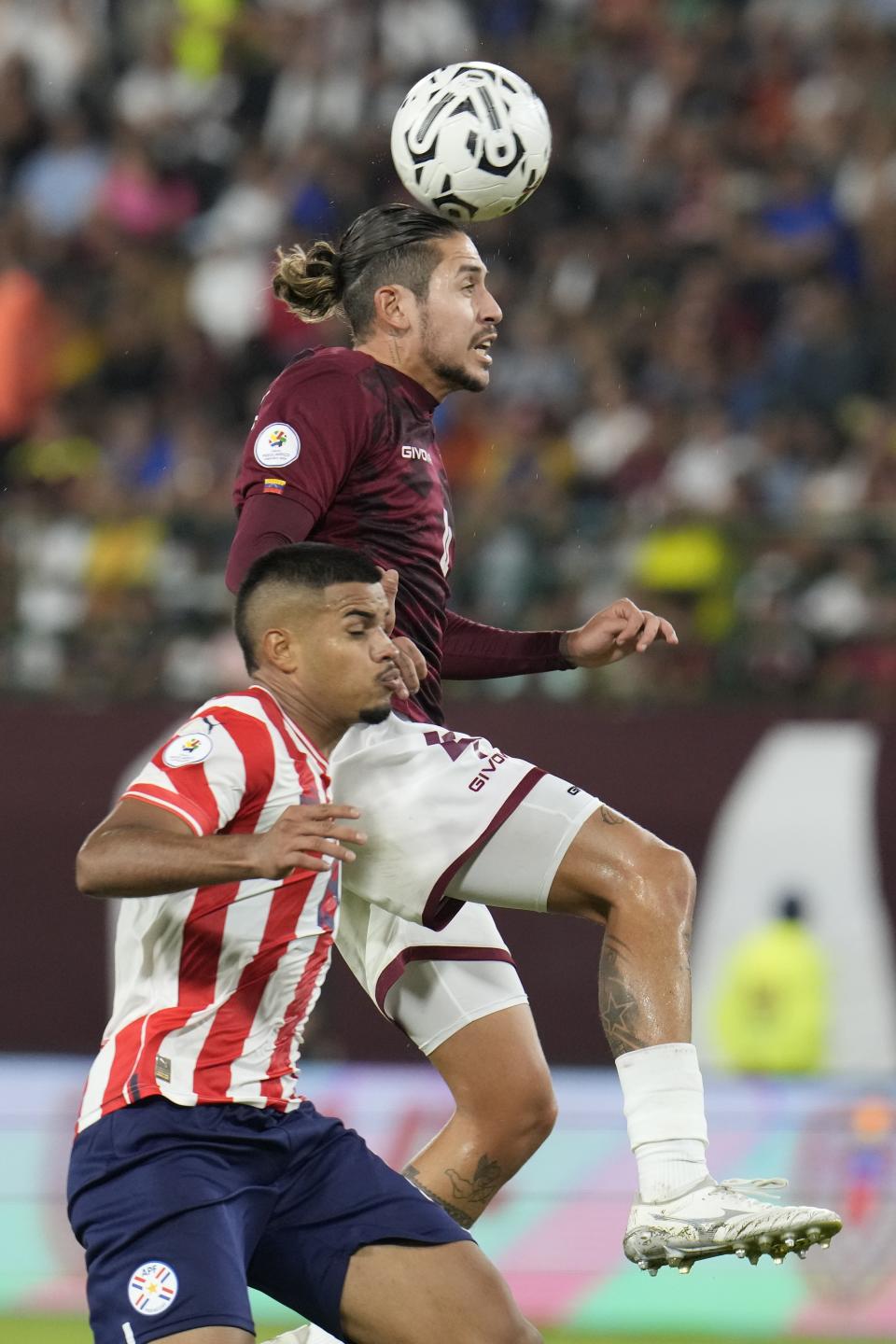 Venezuela's Andrés Ferro, top, heads the ball challenged by Paraguay's Marcelo Pérez during a South America's under-23 pre-Olympic tournament soccer match at Brigido Iriarte stadium in Caracas, Venezuela, Sunday, Feb. 11, 2024. (AP Photo/Ariana Cubillos)