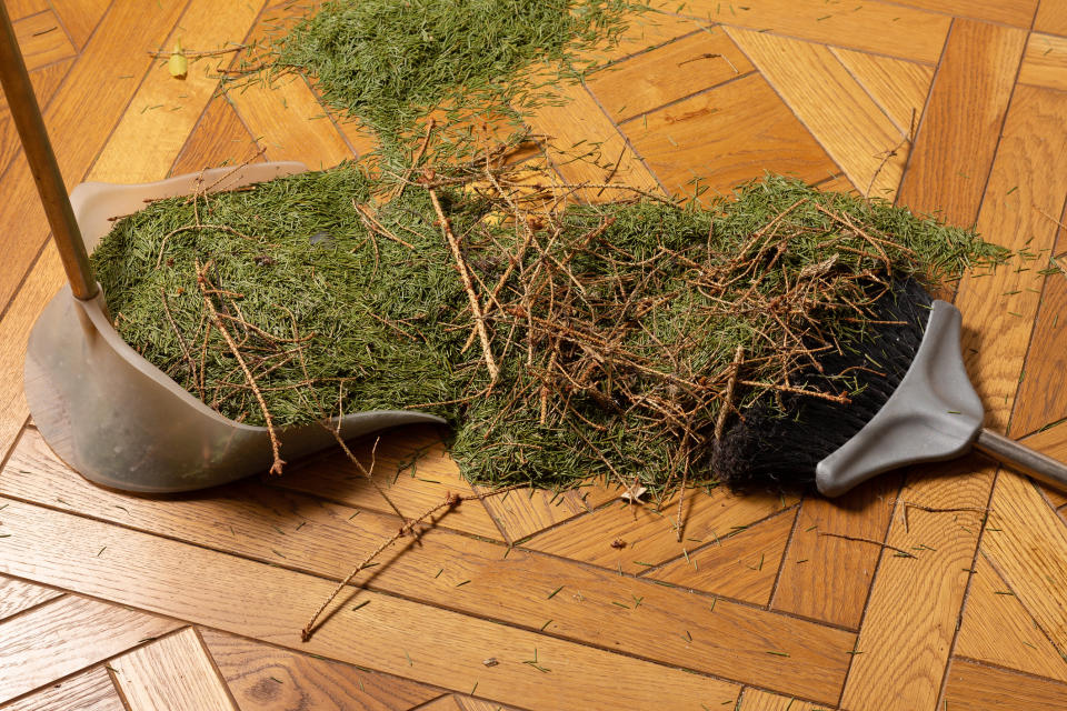 Christmas tree remains being swept away on floor. (Getty Images)