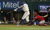 Texas Rangers Eli White, left, hits a two run RBI single in front of Los Angeles Angels catcher Austin Romine (19) during the first inning of a baseball game in Arlington, Texas, Monday, May 16, 2022. Rangers Jonah Heim and Sam Huff scored on the play. The Ranges won 7-4. (AP Photo/LM Otero)