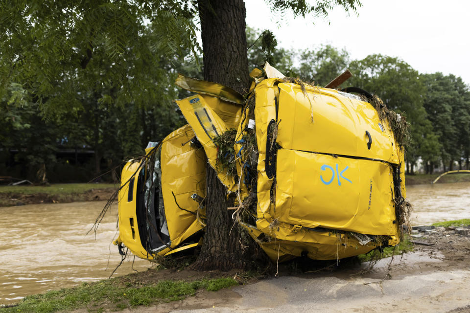 A car washed up by flood waters hangs on a tree while the river Ahr can be seen in the background in Bad Neuenahr, Germany, July 16, 2021. Massive rainfall has caused flooding in Bad Neuenahr in Rhineland-Palatinate as well as in the whole district of Ahrweiler. Severe flooding in Germany and Belgium turned streams and streets into raging torrents that swept away cars and caused houses to collapse. (Philipp von Ditfurth/dpa via AP)