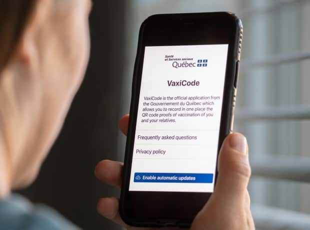 A woman looks at the Quebec government's new vaccine passport called VaxiCode on a phone in Montreal, Wednesday, August 25, 2021, as the COVID-19 pandemic continues in Canada and around the world.  (Graham Hughes/The Canadian Press - image credit)