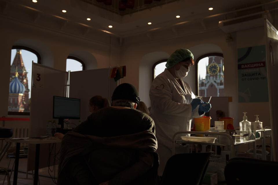 A medical worker prepares a shot of Russia's Sputnik Lite coronavirus vaccine at a vaccination center in the GUM, State Department store, in Red Square with the Spasskaya Tower, right, and the St. Basil Cathedral in the background, in Moscow, Russia, Tuesday, Oct. 26, 2021. The daily number of COVID-19 deaths in Russia hit another high Tuesday amid a surge in infections that forced the Kremlin to order most Russians to stay off work starting this week. (AP Photo/Pavel Golovkin)