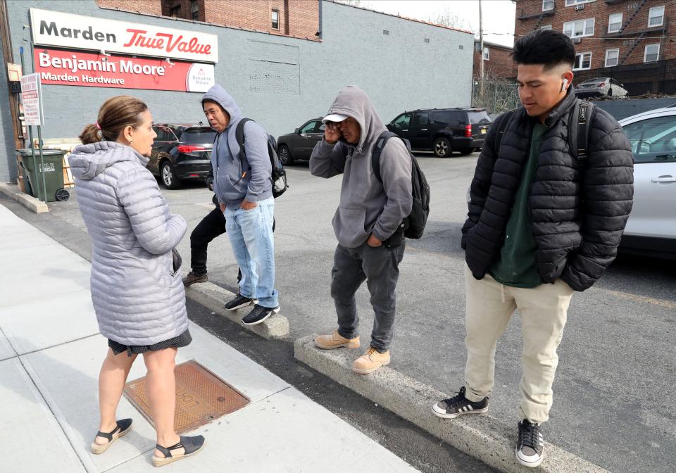 Janet Hernandez, the Westchester coordinator for Catholic Charities, chats with day laborers seeking work, as they waits for jobs along Yonkers Avenue in Yonkers, April 12, 2023. 