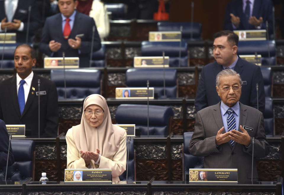 Malaysian Prime Minister Mahathir Mohamad, right, and Deputy Prime Minister Wan Azizah Ismail, pray during a parliament session in Kuala Lumpur, Monday, Oct. 15, 2018. Charismatic Malaysian politician Anwar Ibrahim won a by-election for a parliamentary seat with a landslide victory on Saturday in a grand political comeback to help him prepare for his eventual takeover from Prime Minister Mahathir. (AP Photo/Yam G-Jun)