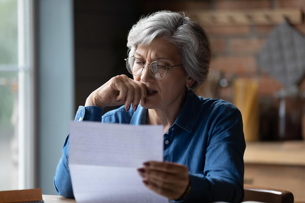 Distressed old age hispanic female checks bills in home office