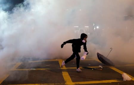 An anti-extradition demonstrator runs away from tear gas, after a march to call for democratic reforms, in Hong Kong