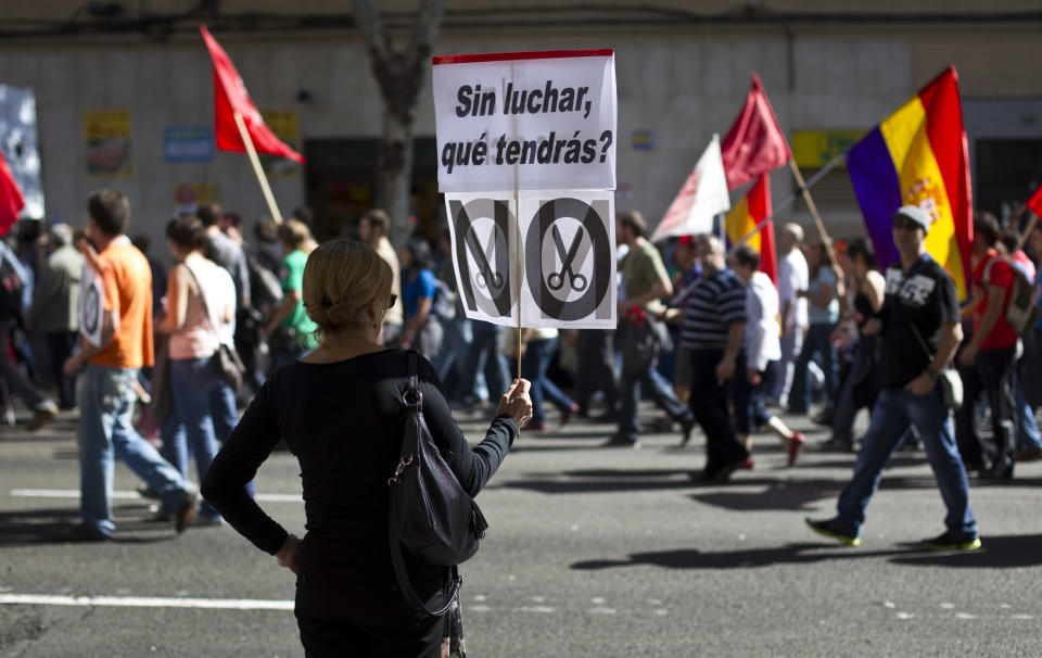 A woman holds a banner reading 'Without fighting, what would you get?' during a demonstration in Madrid, Spain, Sunday, Oct. 7, 2012. Thousands of people called by 150 organizations are marching in 56 Spanish cities to protest punishing austerity cuts they say will only increase unemployment and job insecurity. (AP Photo/Alberto Di Lolli)