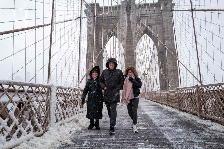 La gente cruza el Puente de Brooklyn bajo la nieve en Manhattan mientras una gran tormenta invernal atraviesa el área.