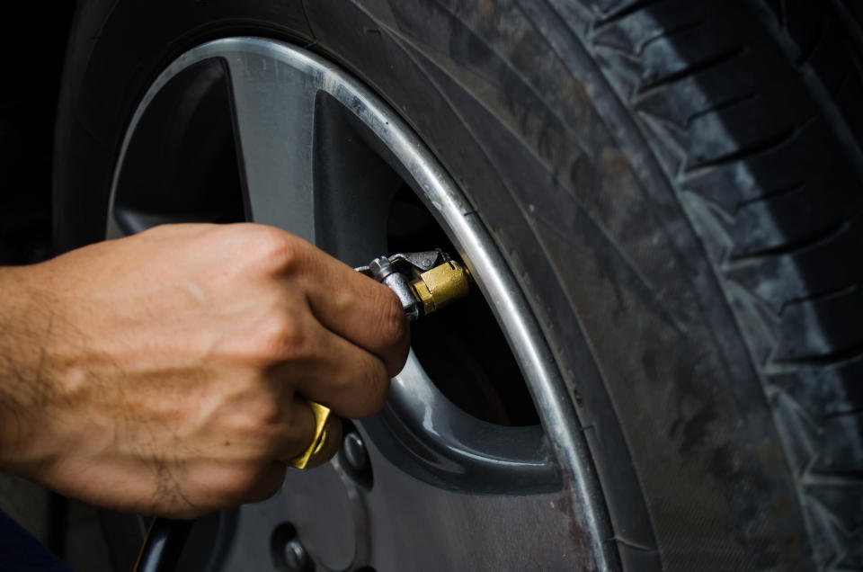 man refilling air into a car tyre