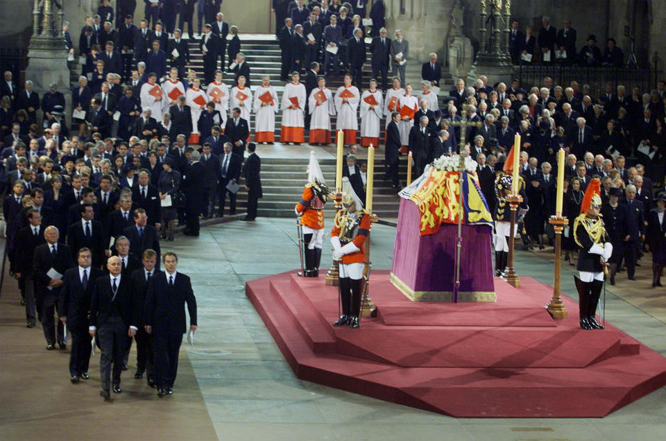 FILE - Britain's Prime Minister Tony Blair, front right, leader of the Liberal Democrats Charles Kennedy, front second right, Iain Duncan-Smith, the leader of the Conservative Party and Deputy Prime Minister John Prescott, front left, file past officers from the Household Cavalry standing in vigil at the coffin of Britain's Queen Elizabeth the Queen Mother as it lies in state in Westminster Hall in London Friday, April 5, 2002. Hundreds of thousands of people are expected to flock to London’s medieval Westminster Hall from Wednesday, Sept. 14, 2022, to pay their respects to Queen Elizabeth II, whose coffin will lie in state for four days until her funeral on Monday. (AP Photo/Santiago Lyon/Pool, File)