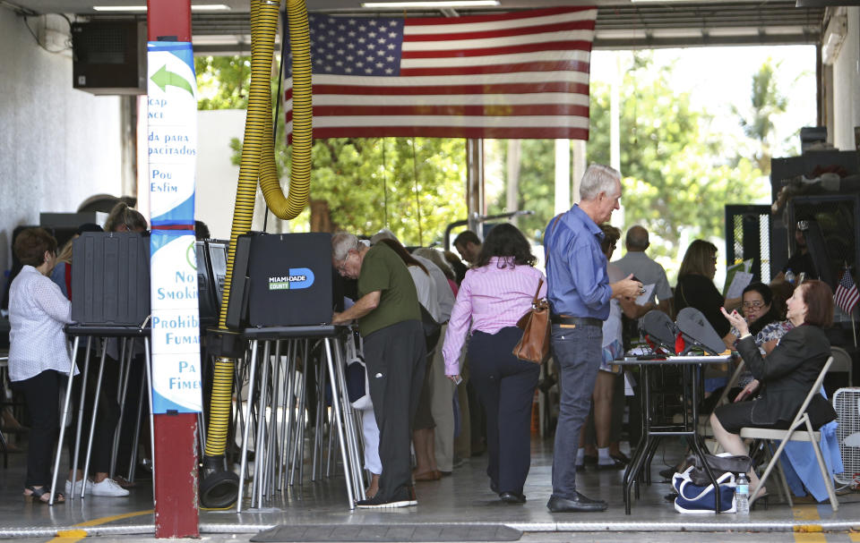 Polling workers help people to check in at Miami Beach Fire Station No. 3 on Tuesday, Nov. 6, 2018, in Miami-Dade County, Fla. (David Santiago/Miami Herald via AP)