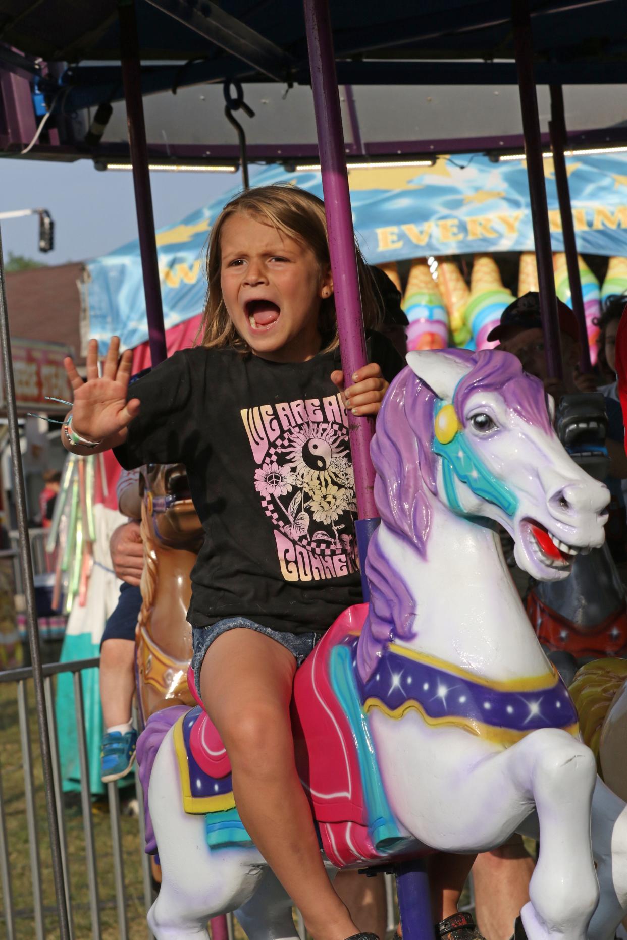 Karsyn Gosche, 6, of Gibsonburg, calls out to her dad as she rides the merry- go-round, at the Gibsonburg Homecoming Festival on Wednesday night.