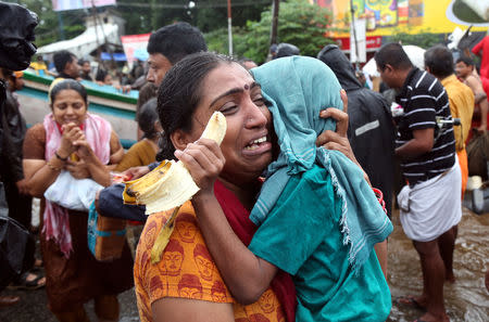 A woman cries as she holds her son after they were evacuated from a flooded area in Aluva in Kerala, India, August 18, 2018. REUTERS/Sivaram V