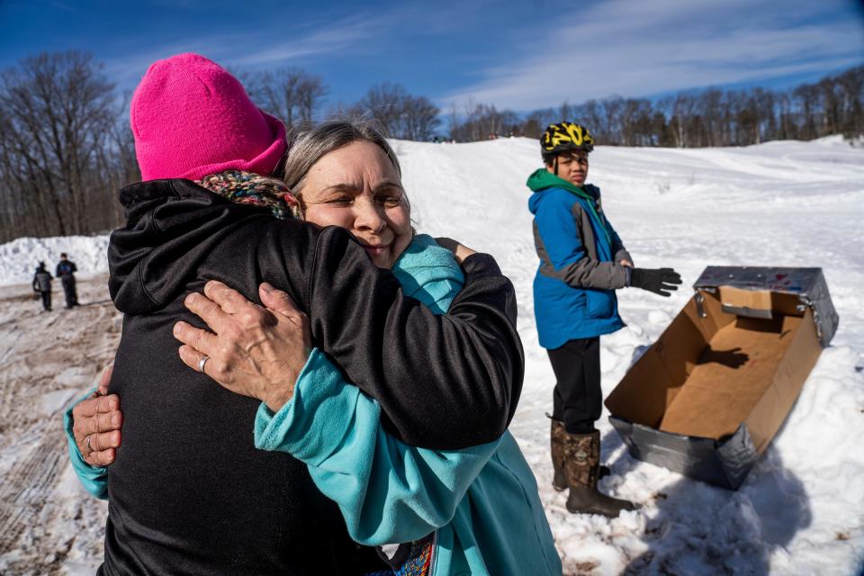 Geriann Bialkowski, center, hugs Denise Venturato as they waited for the start of the K.I. Sawyer Cardboard Sled Races on Feb. 11, 2023.